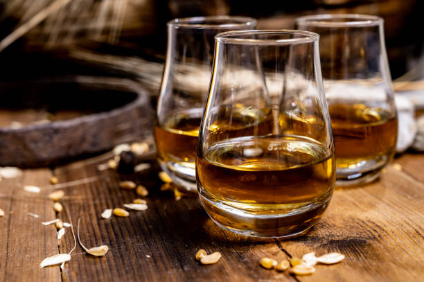speyside scotch whisky proeverij op oude donkere houten vintage tafel met gerstkorrels - spey scotland stockfoto's en -beelden