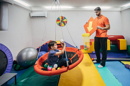 Two people, male physical therapist and boy on physiotherapy, improving sensory perception.