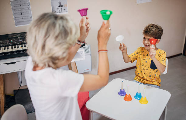 Boy with female teacher on music class Two people, young boy on music class with female teacher, having a music therapy together playing musical bells. music therapy kids stock pictures, royalty-free photos & images