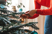 female hands decorating christmas tree with golden retro christmas ball