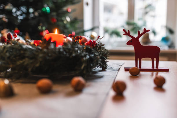 kandel des adventskranzes brennt vor festlichem weihnachtsbaum - adventskranz stock-fotos und bilder