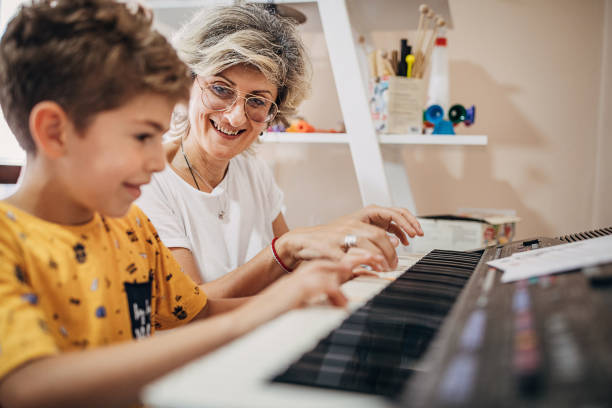 istock Boy learning how to play synthesizer with his music teacher 1270622956