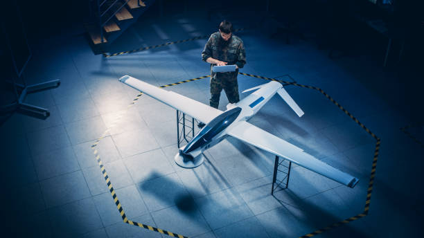 istock Army Aerospace Engineer Work On Unmanned Aerial Vehicle / Drone. Uniformed Aviation Expert Using Laptop. Industrial Facility with Surveillance, Warfare Tactics, Attack Machine. Elevated Shot 1270623379