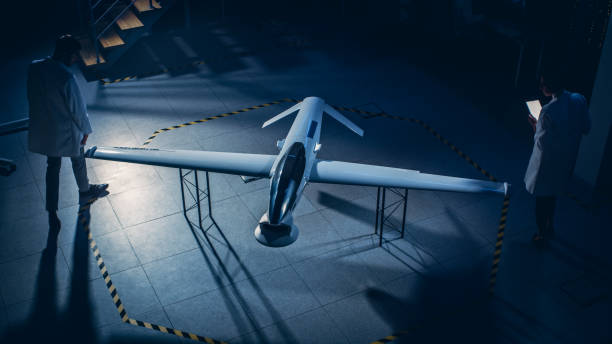 istock Two Aerospace Engineers Work On Unmanned Aerial Vehicle / Drone Prototype. Aviation Scientists Talking, Using Tablet Computer. Industrial Laboratory with Surveillance Military Aircraft. Elevated Shot 1270623426