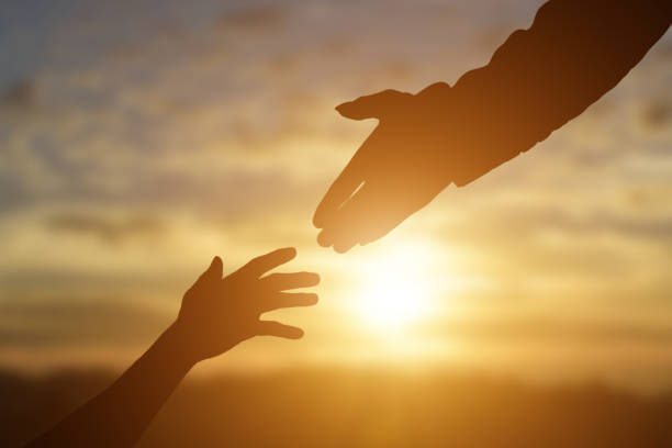 istock Silhouette of giving a helping hand, hope and support each other over sunset 1270623736