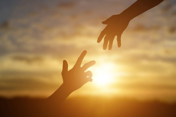 istock Silhouette of giving a helping hand, hope and support each other over sunset 1270623754