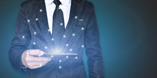 istock Businessman holding smartphone with network connection on blue background. Wireless connect futuristic concept. 1270624956