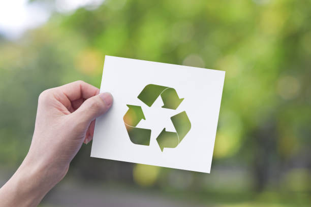 Environment concept. Hand holding white paper with recycle symbol on green bokeh background. stock photo