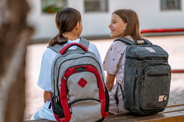 istock Two schoolgirls sitting on a wooden bench 1270628570