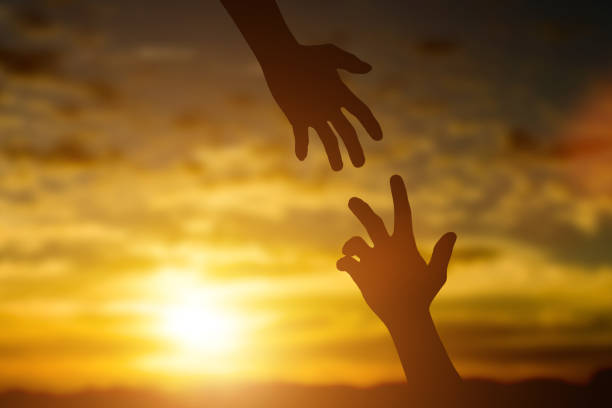 istock Silhouette of giving a help hand, hope and support each other over sunset background. 1270628884