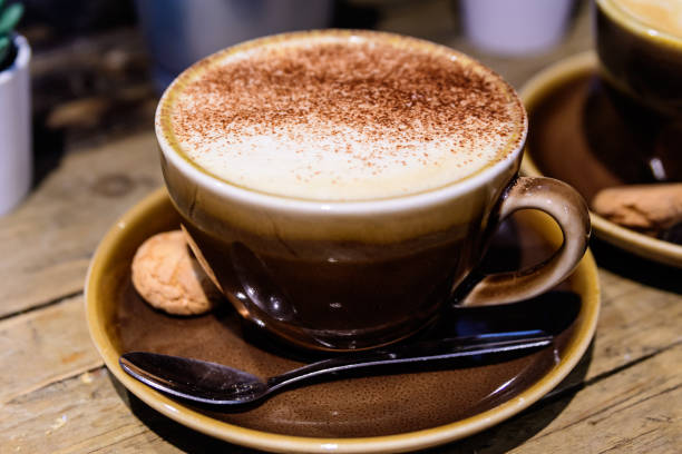 istock One brown cup with hot coffee - Italian cappuccino with cinnamon - on a rustic wooden table in a café, soft focus 1270631128
