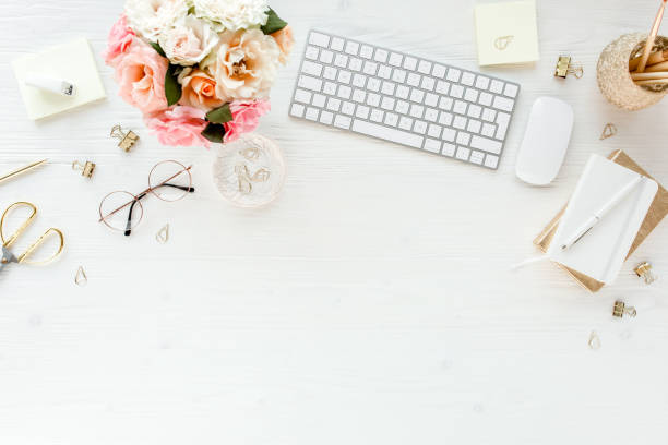 istock Flat lay women's office desk. Female workspace with computer, pink roses flowers, accessories, golden diary, glasses on white background. Top view 1270636003