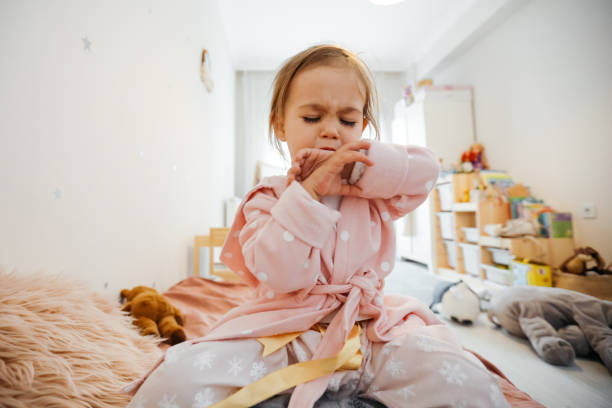 niña enferma tosiendo en la cama - tosiendo fotografías e imágenes de stock