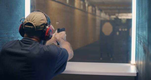 Professional shooter firing at target Back view of middle aged man shooting rifle fast then pushing button and waiting for target to move closer in range target shooting stock pictures, royalty-free photos & images