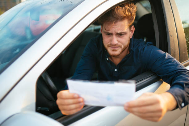 zdenerwowany młody człowiek dostaje bilet parkingowy - driving car traffic men zdjęcia i obrazy z banku zdjęć