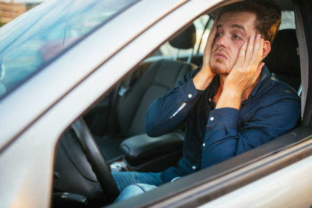 un jeune homme attend désespérément dans l’embouteillage - bouchon photos et images de collection