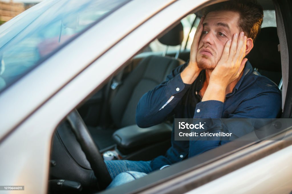 A young man desperately waits in the traffic jam Desperate young driver, can't stand the traffic jam Driving Stock Photo