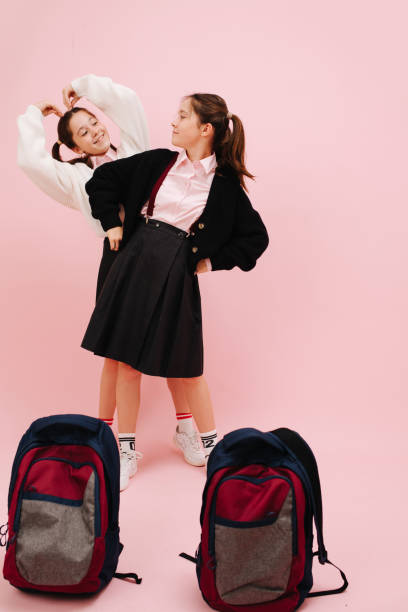 istock Playful twin schoolgirls, tilting at different sides, looking at each other 1270646926