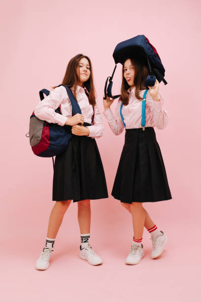 istock Happy little twin schoolgirls posing with their backpacks. Low angle 1270646972