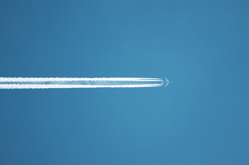 Close up on airplane contrail against clear blue sky