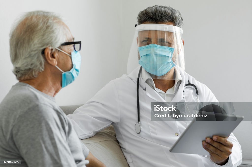 Doctor visiting his patient at his home Protective Face Mask Stock Photo