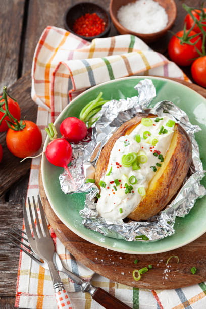 Baked potato with sour cream Baked potato with sour cream and fresh herbs baked potato sour cream stock pictures, royalty-free photos & images