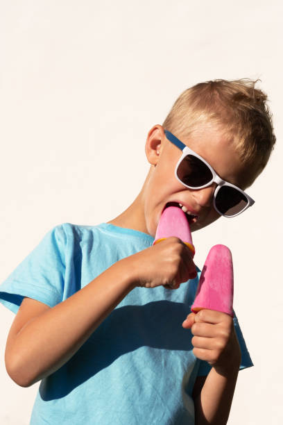 istock Charming boy tries to bite off a pink plastic ice cream thinking it's real 1270658354