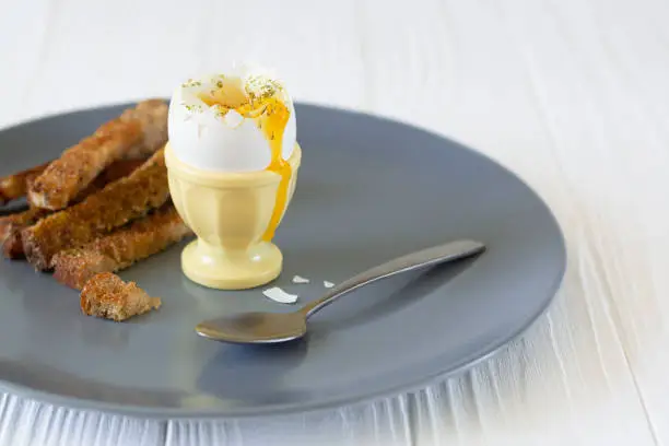 Delicious soft boiled egg in an eggcup with toasted bread for breakfast