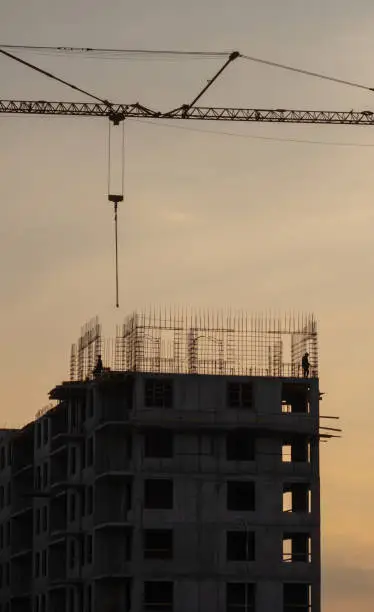 Photo of Silhouettes of tower cranes against the evening sky. House under construction. Industrial skyline