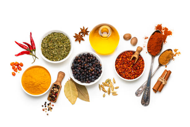 Spices variation on white background. Overhead view Cooking backgrounds: overhead view of several bowls and spoons with multicolored spices shot on white background. The composition includes dried oregano, turmeric, peppercorns, chili pepper cinnamon, bay leaves, cardamom, nutmeg and olive oil. High resolution 42Mp studio digital capture taken with Sony A7rII and Sony FE 90mm f2.8 macro G OSS lens pepper seasoning stock pictures, royalty-free photos & images