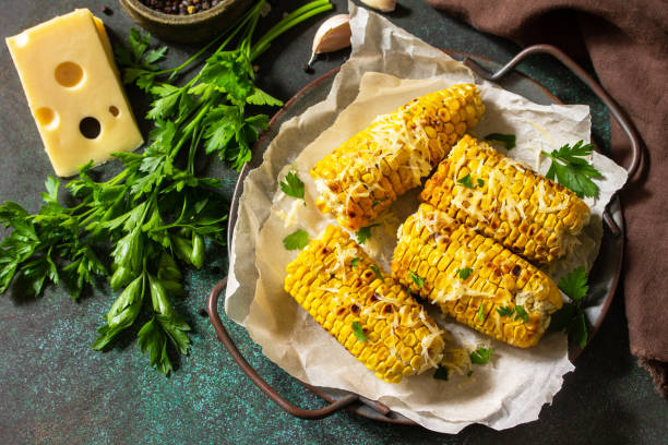 istock Summer vegan dinner or snacks. Grilled corn with garlic butter, served with cheese on a dark stone table top. Copy space. 1270664437