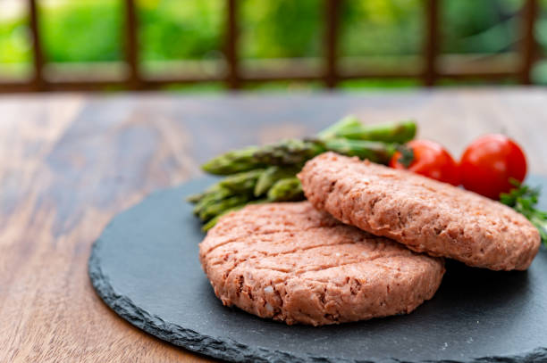 zutaten für schmackhaftes veganes abendessen, fleischfreies steak auf pflanzenbasis, grünen spargel und rote tomaten - fleischersatz stock-fotos und bilder