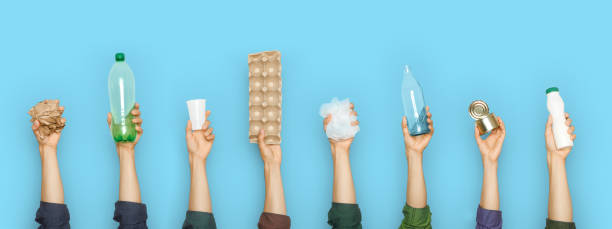 Hands holding different trash , plastic, metal, glass and paper on a blue background.