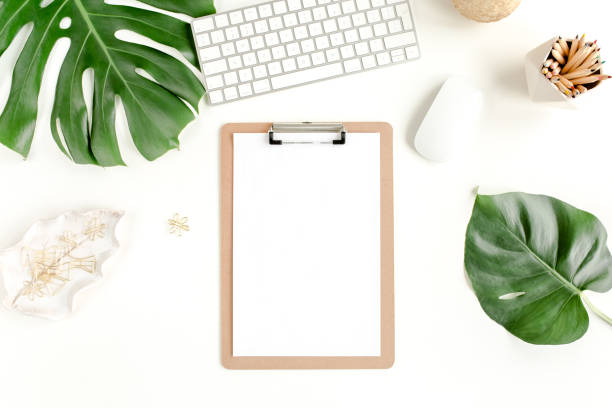 istock Flat lay home office desk. Female workspace with computer, clipboard, tropical palm leaves Monstera, accessories on white background. Top view 1270666943