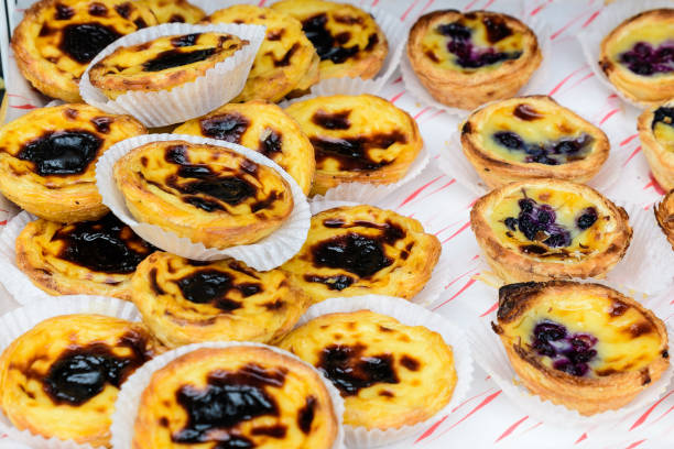 istock Diffeent types of Portuguese traditional desert - Pasteis de Nata (Pastel de Nata) - freshly cooked and displayed for sale at a street food market, soft focus 1270668931