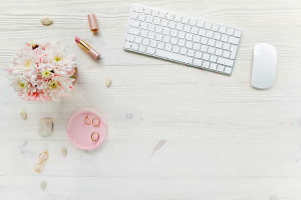 istock Top view office desk. Workspace with, computer, chrysanthemum, clipboard. Women's fashion accessories isolated on white wooden background. Flat lay 1270669082