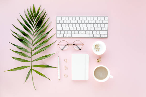 istock Office table desk with computer, green leaves palm, clipboard. Top view. Flat lay. Home office workspace. Women's accessories on pink background 1270670422