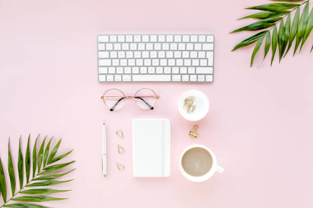 istock Office table desk with computer, green leaves palm, clipboard. Top view. Flat lay. Home office workspace. Women's accessories on pink background 1270671211