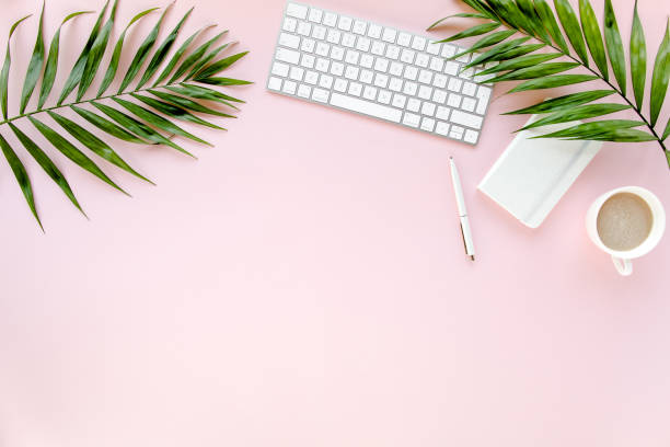 istock Office table desk with computer, green leaves palm, clipboard. Top view. Flat lay. Home office workspace. Women's accessories on pink background 1270671606