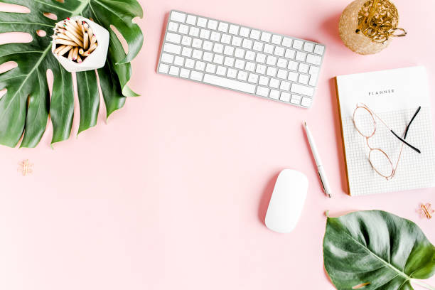 istock Flat lay home office desk. Female workspace with computer, tropical palm leaves Monstera, accessories on pink background. Top view background 1270671633