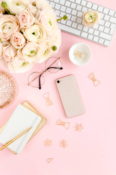 istock Stylized, pink women's home office desk. Workspace with computer, bouquet ranunculus and roses, phone on pink background. Flat lay. Top view 1270673922