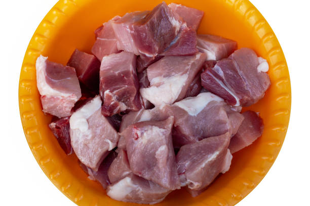 Pieces of meat in an orange plastic bowl. Isolated. Top view.
