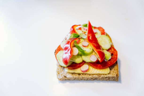 istock Open faced sandwich isolated on white background. Vegetarian sandwich with cheese, tomatoes, cucumber, radish, and red bell pepper 1270676520