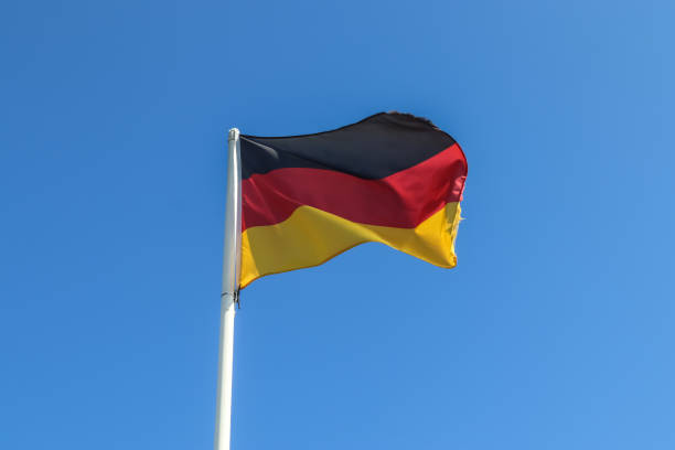 istock Germany flag at a flagpole moving slowly in the wind against the sky 1270678824