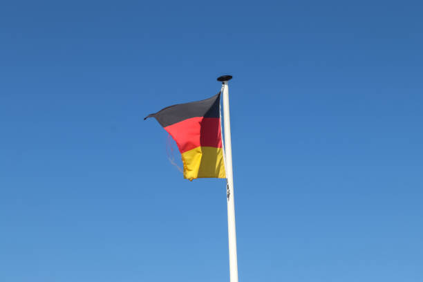istock Germany flag at a flagpole moving slowly in the wind against the sky 1270678975