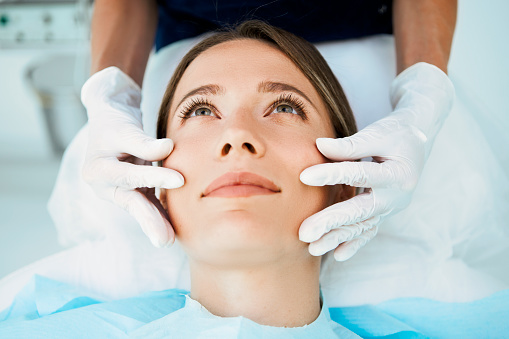 Cosmetologist preparing to doing cosmetic facial treatments for the young woman