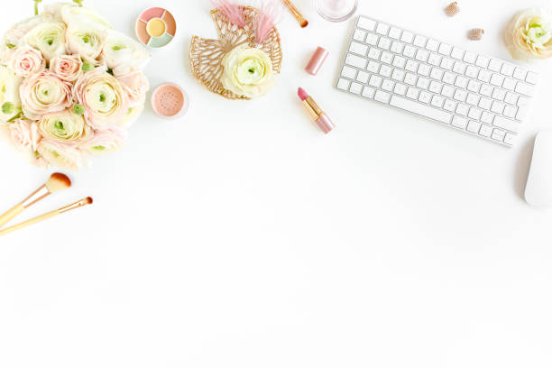 istock Stylized women's home office desk. Workspace with computer, bouquet ranunculus and roses, clipboard on white background. Flat lay. Top view 1270681675