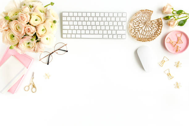 istock Stylized women's home office desk. Workspace with computer, bouquet ranunculus and roses, clipboard on white background. Flat lay. Top view 1270681788