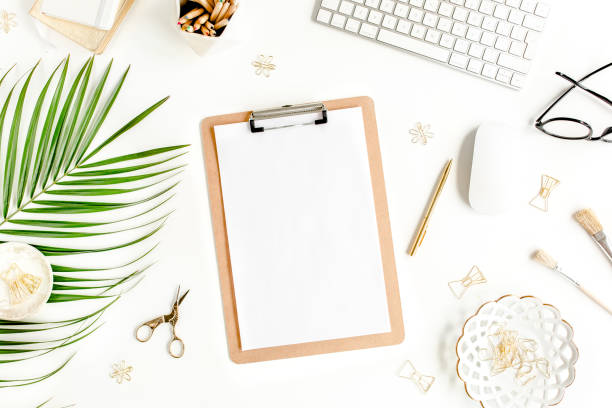 istock Flat lay home office desk. Female workspace with computer, clipboard, tropical palm leaves, accessories on white background. Top view 1270681885