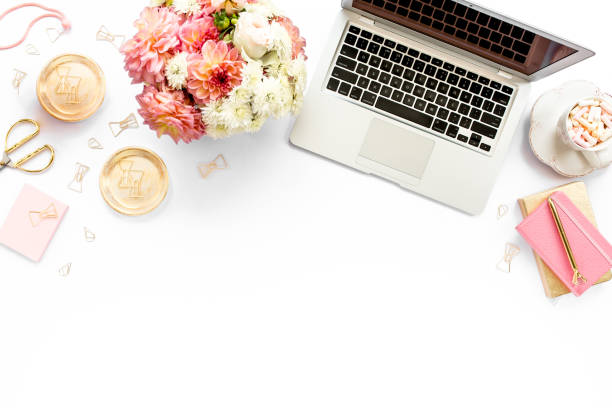 istock Stylized women's home office desk. Workspace with laptop, computer, bouquet ranunculus and roses, clipboard on white background. Flat lay. Top view 1270681966